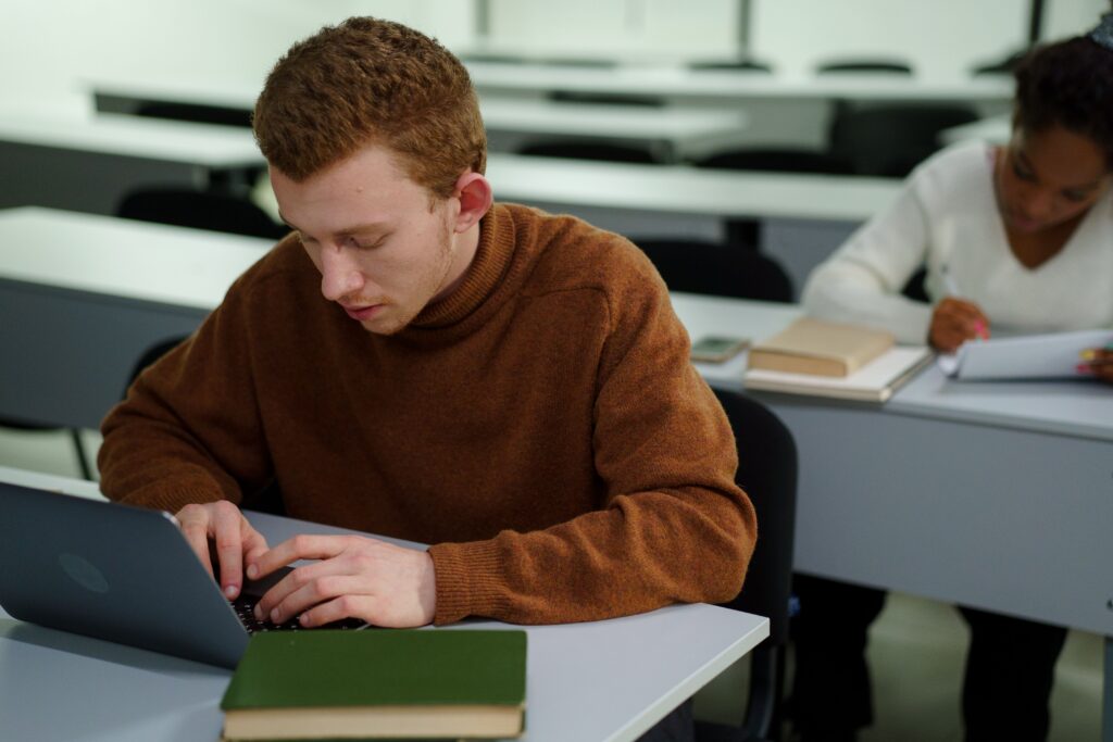 An IT student typing on their laptop while in class